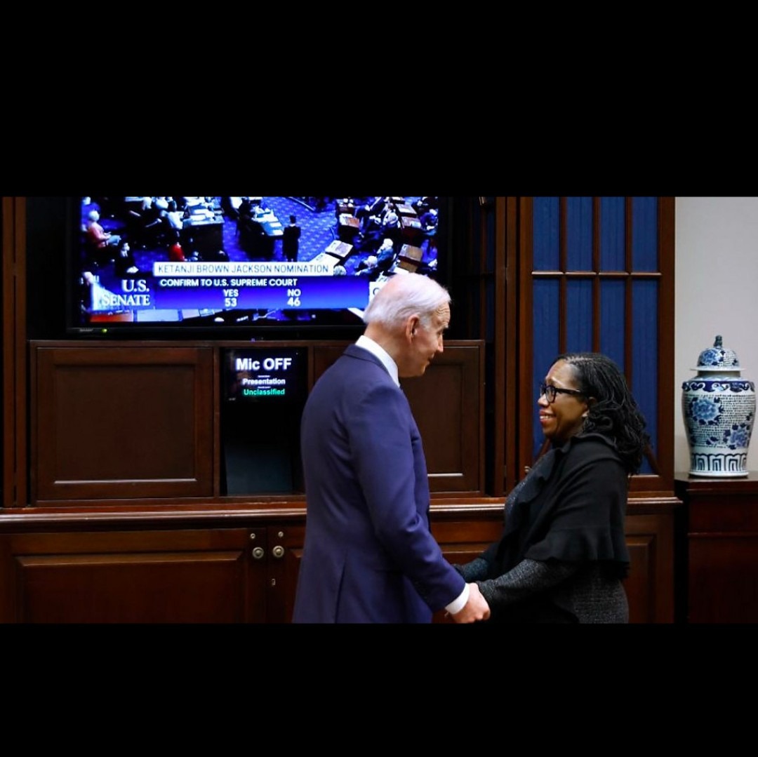 Joe Biden and Ketanji Brown Jackson standing while holding hands